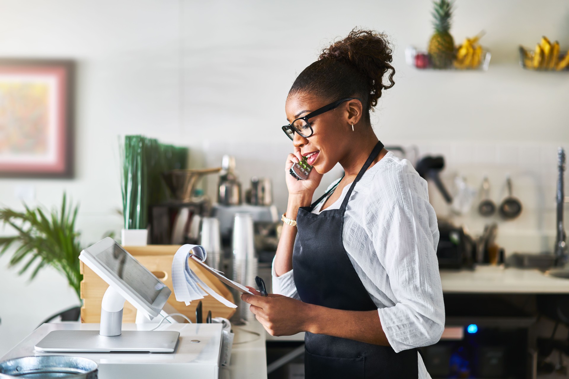 friendly waitress taking order on phone at restaurant and writing on notepad